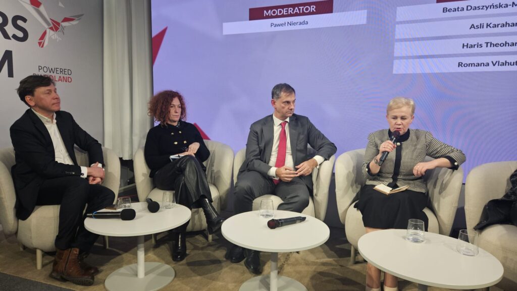 A group of panelists seated at a conference table during a discussion on the Three Seas Initiative at the Leaders Forum in Davos 2026. Participants are engaged in conversation, with microphones and nameplates visible, against a backdrop featuring the event’s branding.