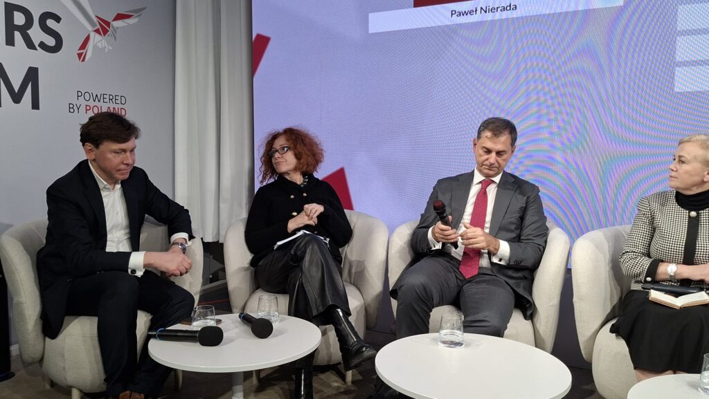 A group of panelists seated at a conference table during a discussion on the Three Seas Initiative at the Leaders Forum in Davos 2026. Participants are engaged in conversation, with microphones and nameplates visible, against a backdrop featuring the event’s branding.